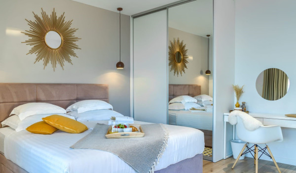 A spacious modern bedroom with access to a terrace with a seating area and a view of the Brač channel