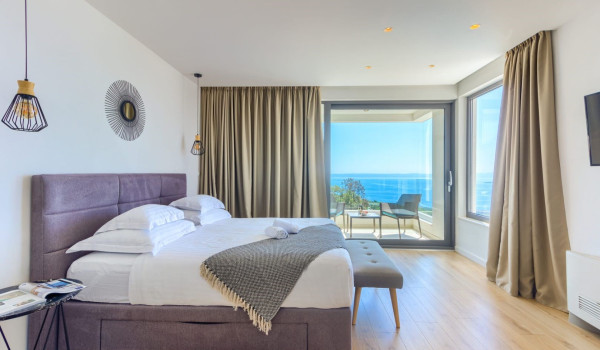 A spacious modern bedroom with access to a terrace with a seating area and a view of the Brač channel