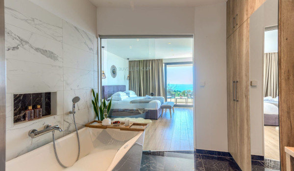 A spacious modern bedroom with access to a terrace with a seating area and a view of the Brač channel
