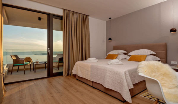 A naturally lit bedroom with a king-size bed and a terrace inside a luxury Croatian villa for rent and vacation