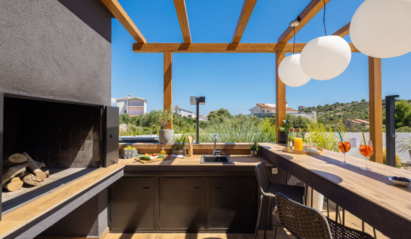 Summer kitchen with a grill, sink and kitchen island in the fenced yard of the luxury Croatia holiday home Indigo