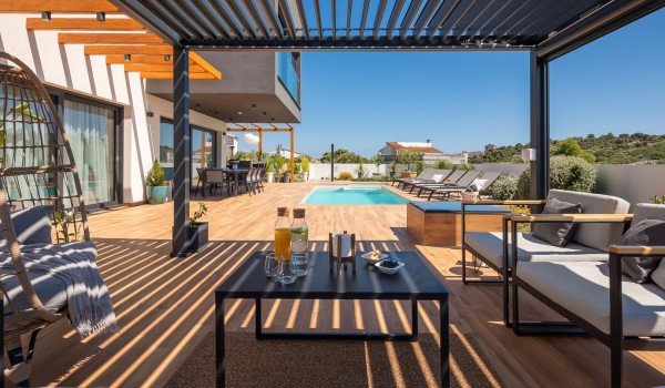 Outdoor seating furniture with a table under a pergola next to the private pool of the luxury Croatia villa with sauna and jacuzzi