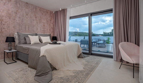 Exit from the contemporary bedroom with a king size bed and a seating corner to the fenced balcony with an outdoor seating furniture