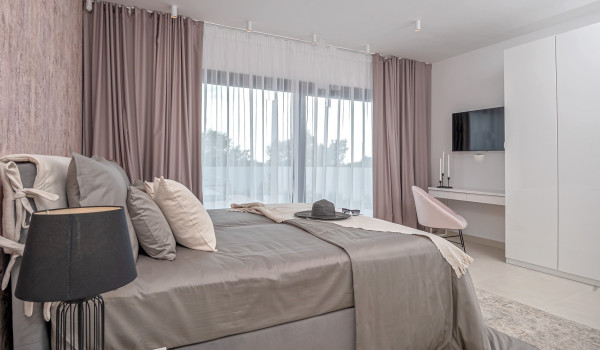 Comfortable king size bed in the modern bedroom with SAT TV and an access to the private balcony