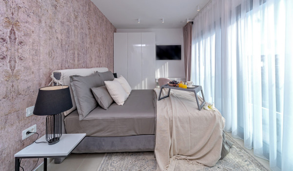 Modern king size bed in the elegant bedroom with an access to the balcony and an SAT TV