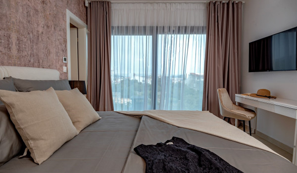 SAT TV in front of the comfortable king size bed in the elegantnly decorated bedroom in the luxury pet-friendly villa Indigo