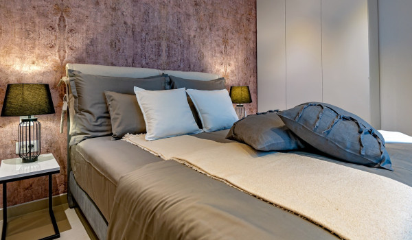 Comfortable king size bed with a nightstand in the modernly decorated bedroom of the luxurious rental home Indigo with pool near Rogoznica