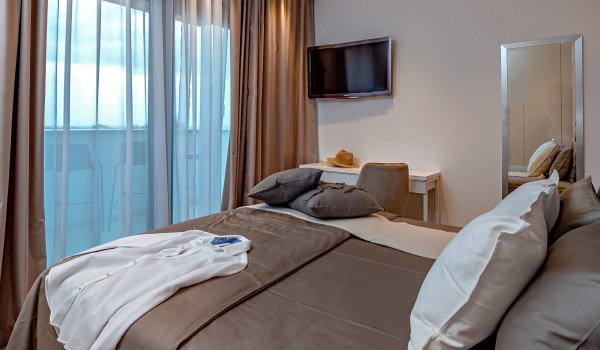 Modernly decorated bedroom with a king size bed, SAT TV and a private access to the fenced balcony with a view of the property