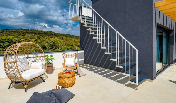 Fenced terrace with an outdoor seating corner in front of the modernly decorated villa Indigo for rent and holiday