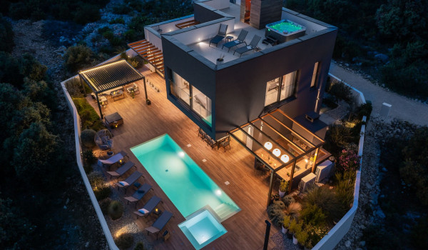 Night shot of the fenced patio of the contemporary holiday home for a family vacation with private pool in Rogoznica
