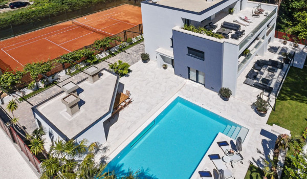 Aerial view of the property of the modern villa Velvet Bourbon Split with a roofed patio and private pool surrounded by sun loungers and tennis court next to the yard