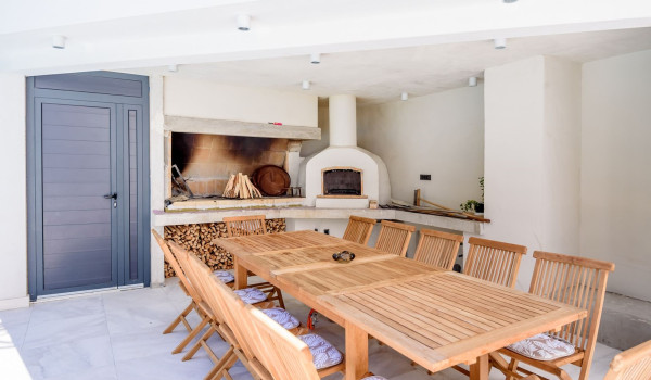 Wood-burning fireplace and dining table with chairs in the summer kitchen in the luxury villa Velvet Bourbon Split