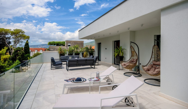 Spacious terrace with outdoor seating and deck chairs on the third floor of the villa with pool