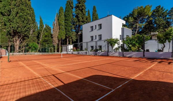 Private tennis court next to modern holiday villa with pool
