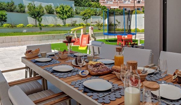 Breakfast served on the outdoor dining table with chairs on the patio of the villa Thalia for rent and vacation