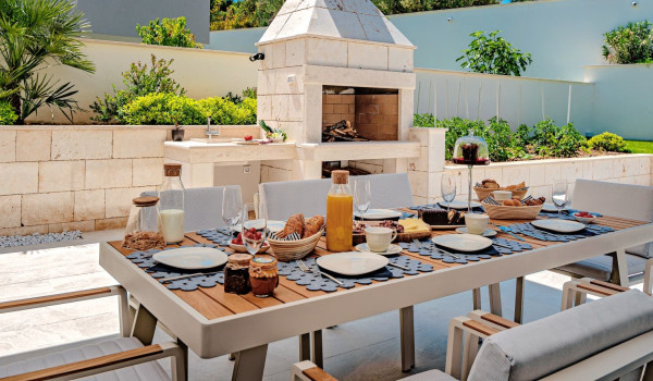 Outdoor dining table with chairs in the yard of the private villa Thalia for holiday in Marina