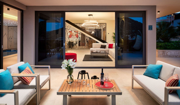 Roofed patio with a seating corner and a table in front of the entrance to the liviing room of the villa Thalia in Marina