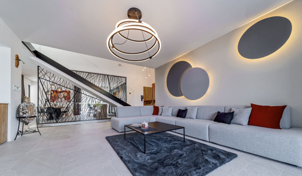 Spacious living room with a corner sofa on the ground floor of the modern rental home Thalia with an indoor pool