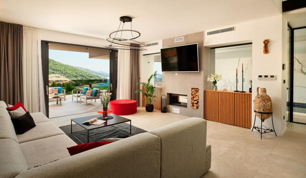 Interior of the modern living room with an angled sofa and SAT TV in the villa Thalia with an indoor pool and gym