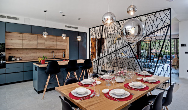 Fully equipped kitchen with a kitchen island and an airy dining area with a wooden table and chairs on the ground floor of the villa Thalia