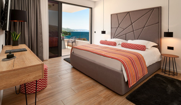 Interior of the airy bedroom with a comfortable king size bed, SAT TV and exit to the balcony