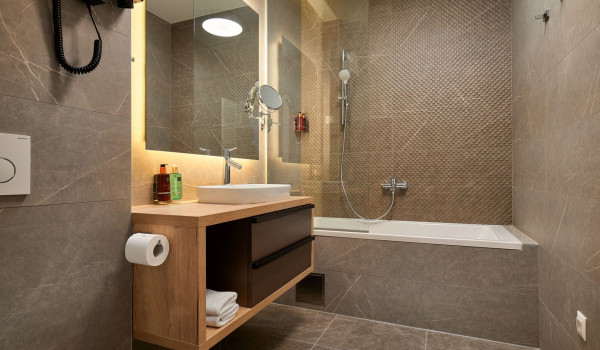 Modernly decorated bathroom with a bathtub, washbasin, mirror and toiletries in the luxury villa Thalia in Marina
