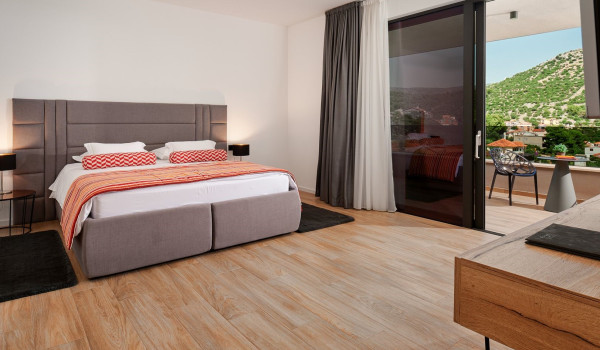 Spacious bedroom with a king size bed, nightstantds, drawers and exit to the balcony with sea view
