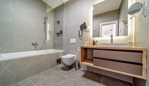 Modernly decorated bathroom with bathtub, toilet, washbasin, mirror and toiletries in the villa Thalia for rent and vacation