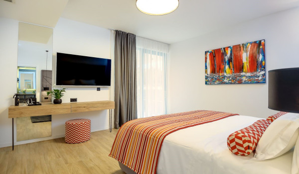 Interior of the modernly decorated bedroom with a comfortable king size bed, SAT TV and sitting corner