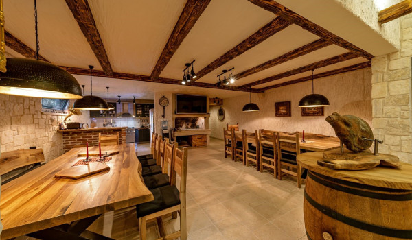 Spacious tavern with tables and wine collection in the basement of the vacation villa Thalia