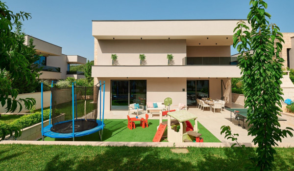 Private landscaped garden with a children's playground on the property of the  modern family villa Thalia in Marina
