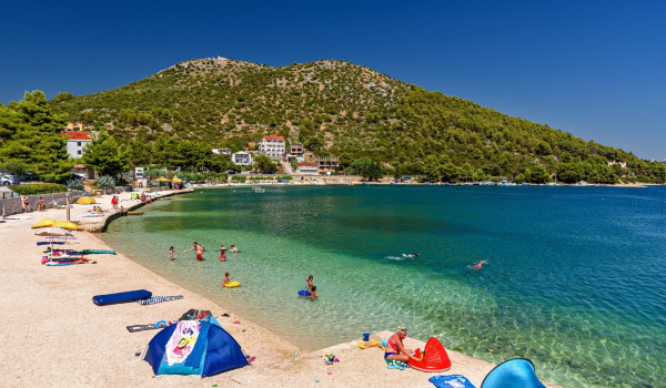Sunny pebble beach in the vicinity of the Croatian vacation villa Thalia with an indoor pool in Marina