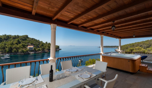 Outdoor dining table and jacuzzi on the balcony of the luxury beachfront villa for family vacation on Korcula island