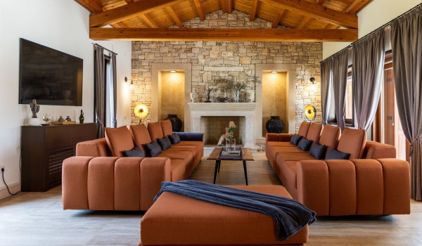 Luxuriously furnished living room with comfortable sofas, TV and white fireplace on the ground floor of a modern villa