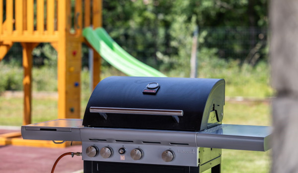 Outdoor gas grill located next to the outdoor kitchen and dining table with chairs
