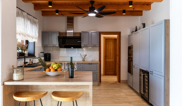 Fully equipped kitchen with a bar and two bar stools inside the ground floor of the Croatian luxury villa for vacation and rent