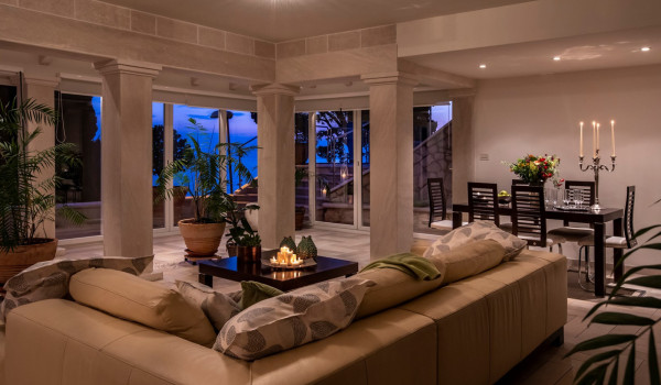 Living room with large comfortable sofa and dining table overlooking the sea from the luxury holiday villa with private pool and concierge service