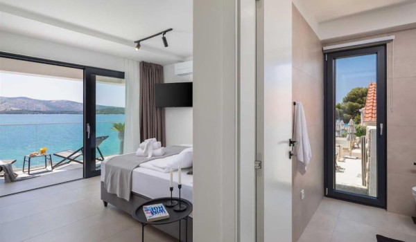 A spacious, modernly decorated bedroom with a view of the crystal blue sea