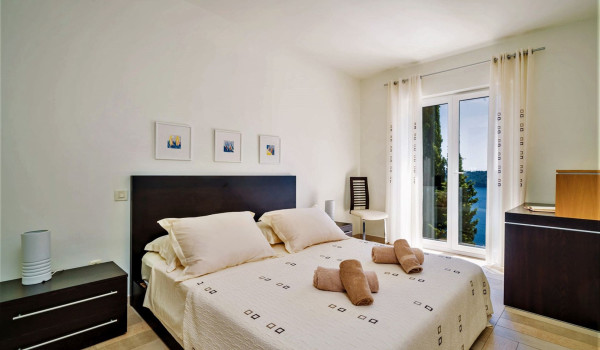 Queen size bed in a bedroom with sea view of the luxury seafront villa for vacation with family and friends