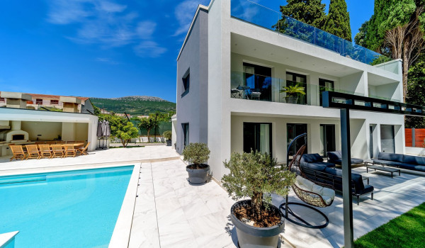 Private fenced yard of a luxury villa for rent with pool, summer kitchen and outdoor seating