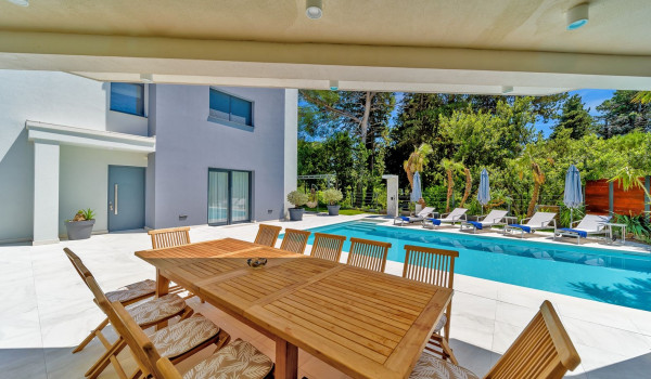 Roofed terrace with outdoor dining table and chairs by the private pool