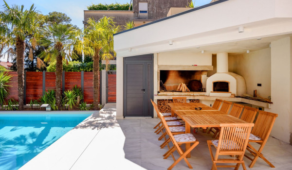 Pool next to the summer kitchen with fireplace in the fenced yard of the newly built villa with pool and tennis court