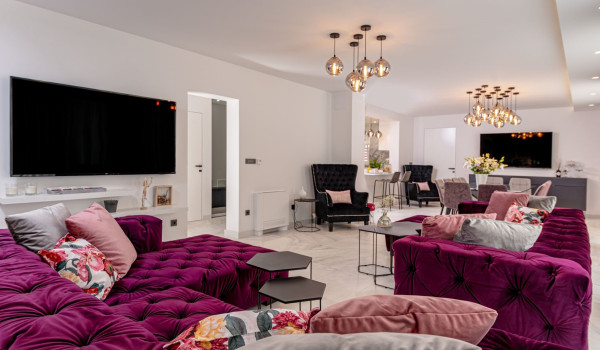 Comfortable, spacious sofa in front of the LCD TV in a comfortably lit living room and dining area with LCD TV in the background