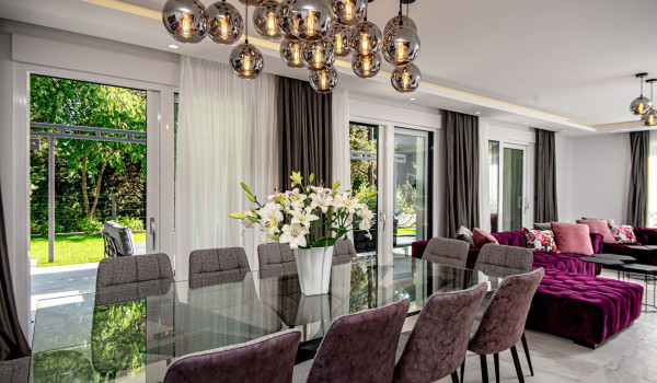 Modern glass table with chairs next to the corner sofa in the living room