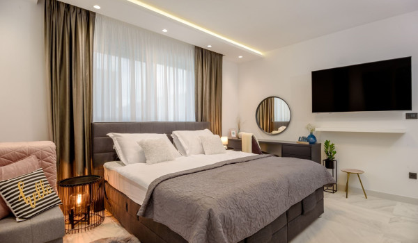 LCD TV next to the king size bed in the modern bedroom of the modern villa Velvet Bourbon Split with pool