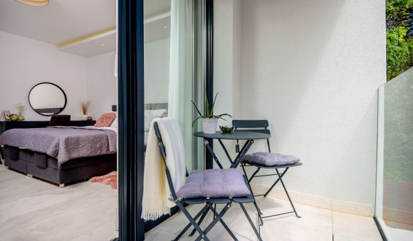 Chairs with an end table on the balcony in the bedroom on the first floor of the modern villa Velvet Bourbon with pool