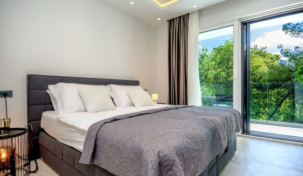 King size bed next to its own exit to the balcony in the modern bedroom of the luxury villa with pool Velvet Bourbon Split