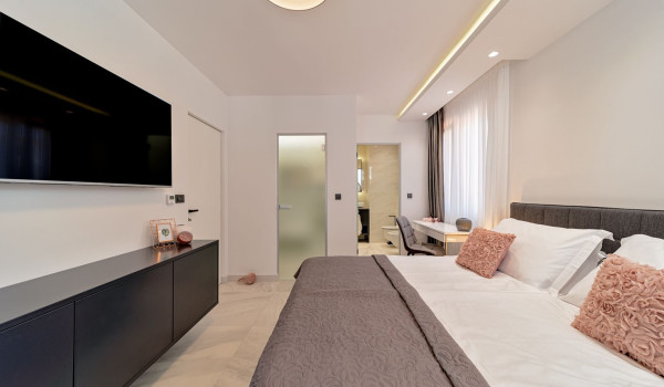 LCD TV in front of a comfortable king size bed in the modern bedroom with an en suite bathroom