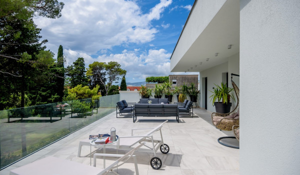 Sun loungers and seating area on the third floor terrace enclosed by glass fence
