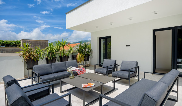 Outdoor seating with end table on the terrace of the third floor of the modern newly built holiday villa by the sea